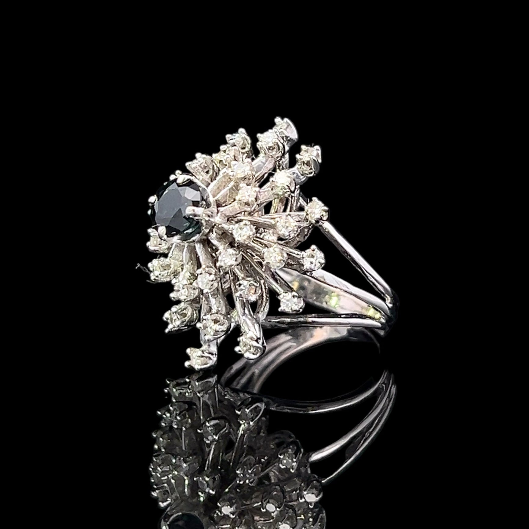 Silver ring with floral design and black gemstone on a black background