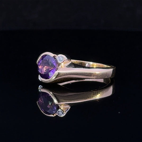 Close up of 14 karat yellow gold ring featuring round amethyst and diamond accents
