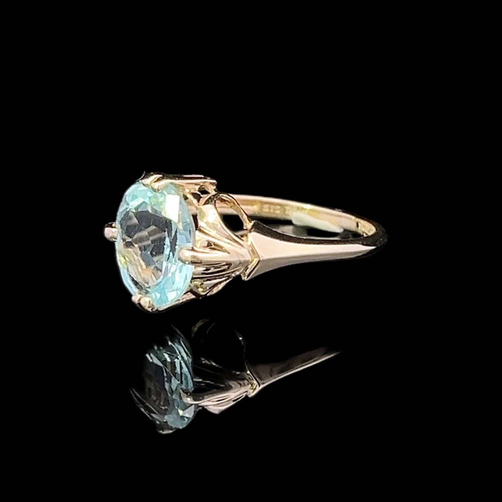 Gold ring with a blue gemstone on a black background