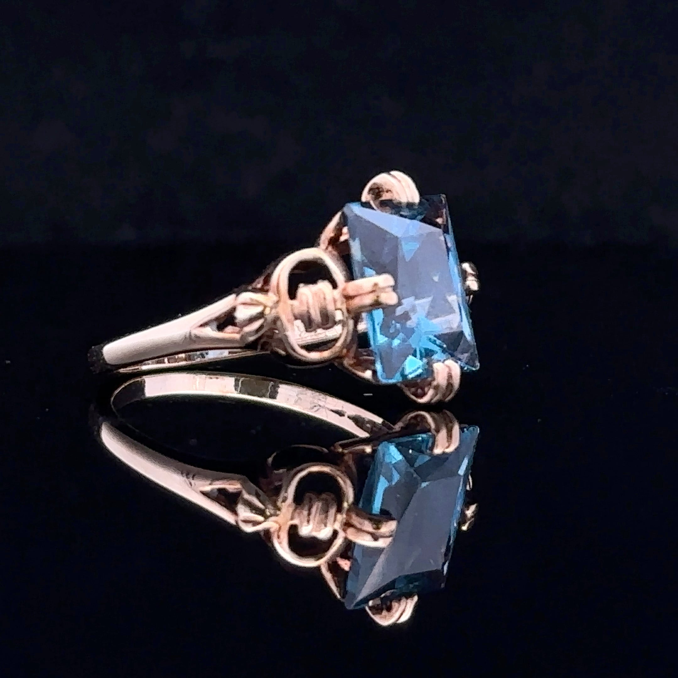 antique-style white gold ring with emerald-cut blue stone
