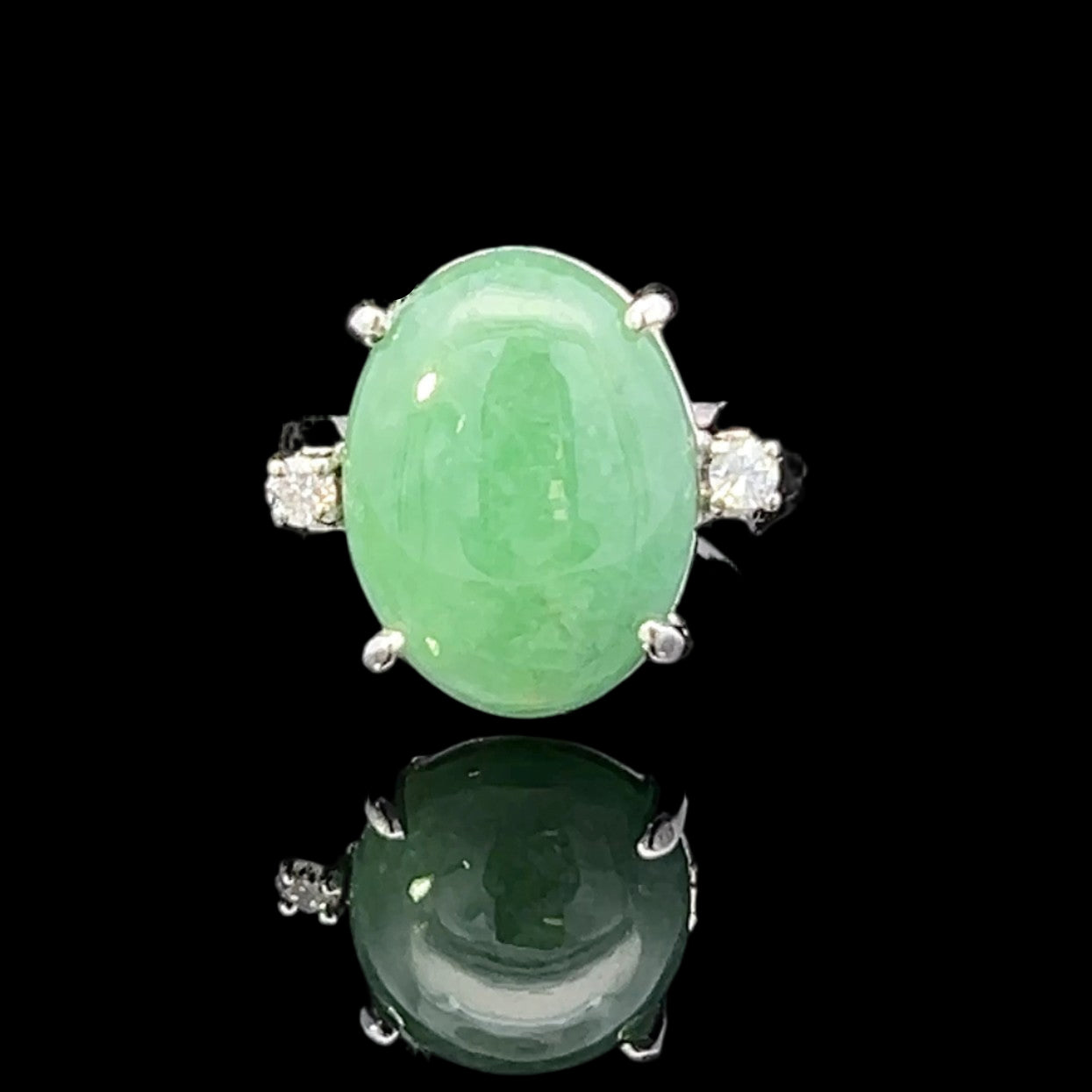 Green jade ring with silver accents on a black background